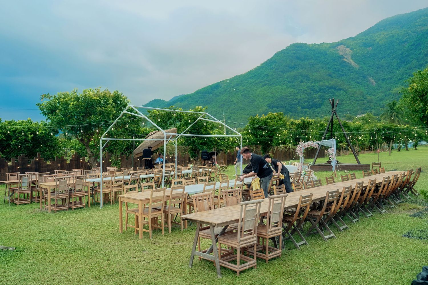 Outdoor wedding ceremony setup with wooden chairs arranged in rows against mountain backdrop.