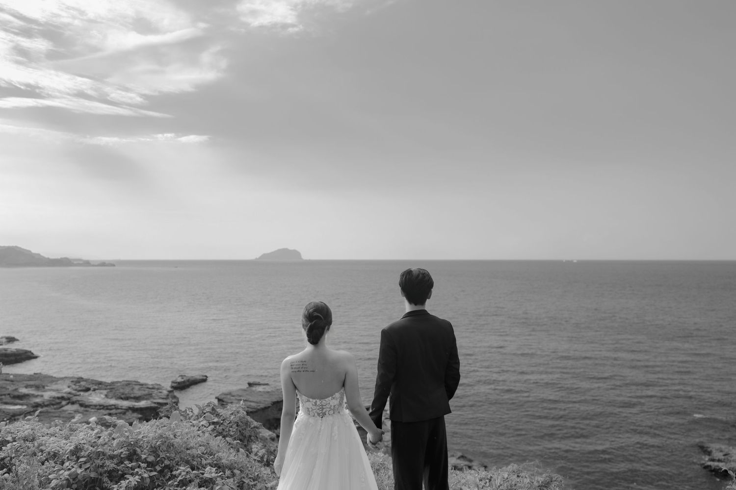 A black and white panoramic photo series showing a couple at their coastal wedding with ocean and mountain views.