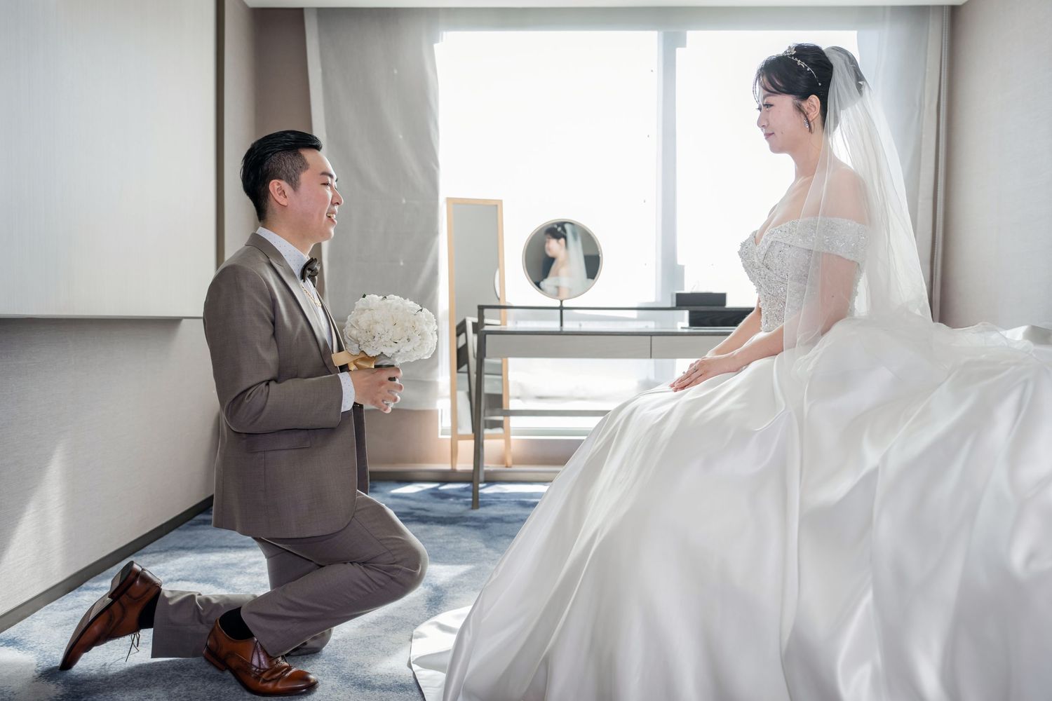 Bride and groom share intimate moments during a minimalist wedding photoshoot in a bright white room.