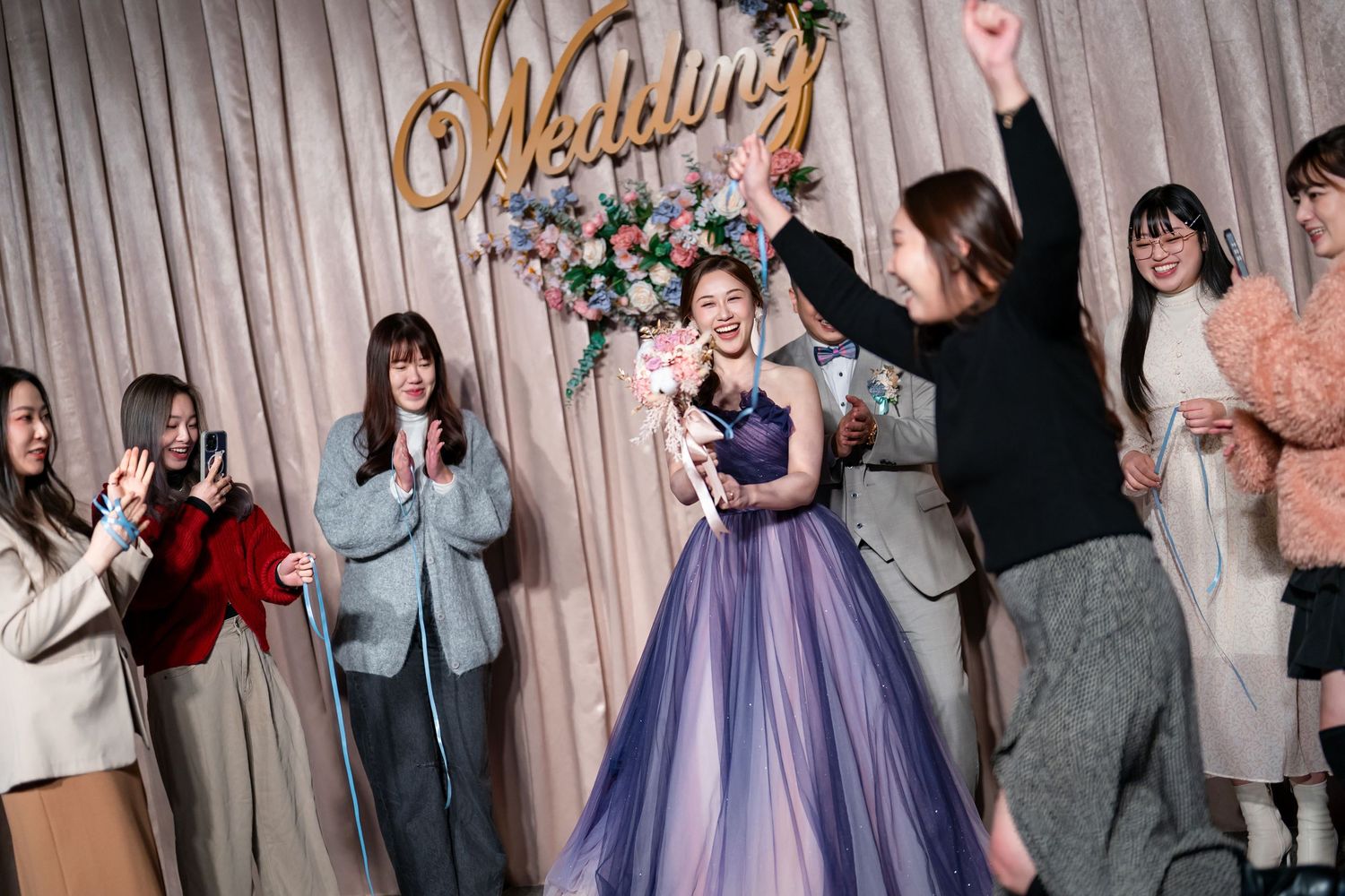 A group of people in formal attire dancing and celebrating at a wedding reception.