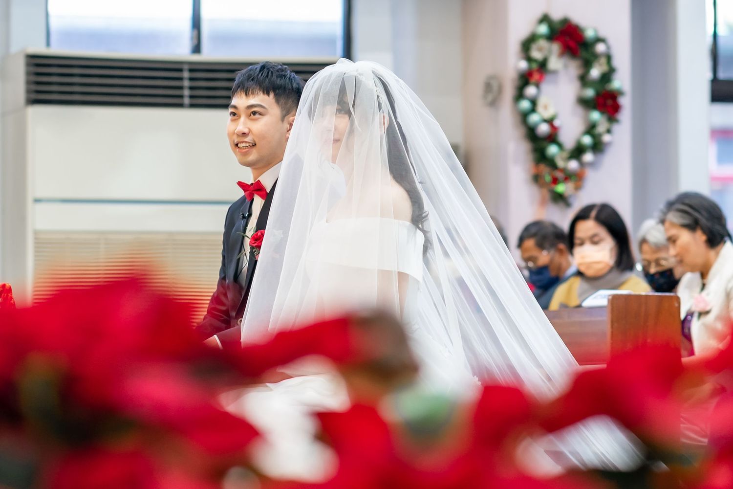 A traditional church wedding ceremony with red poinsettias decorating the space.