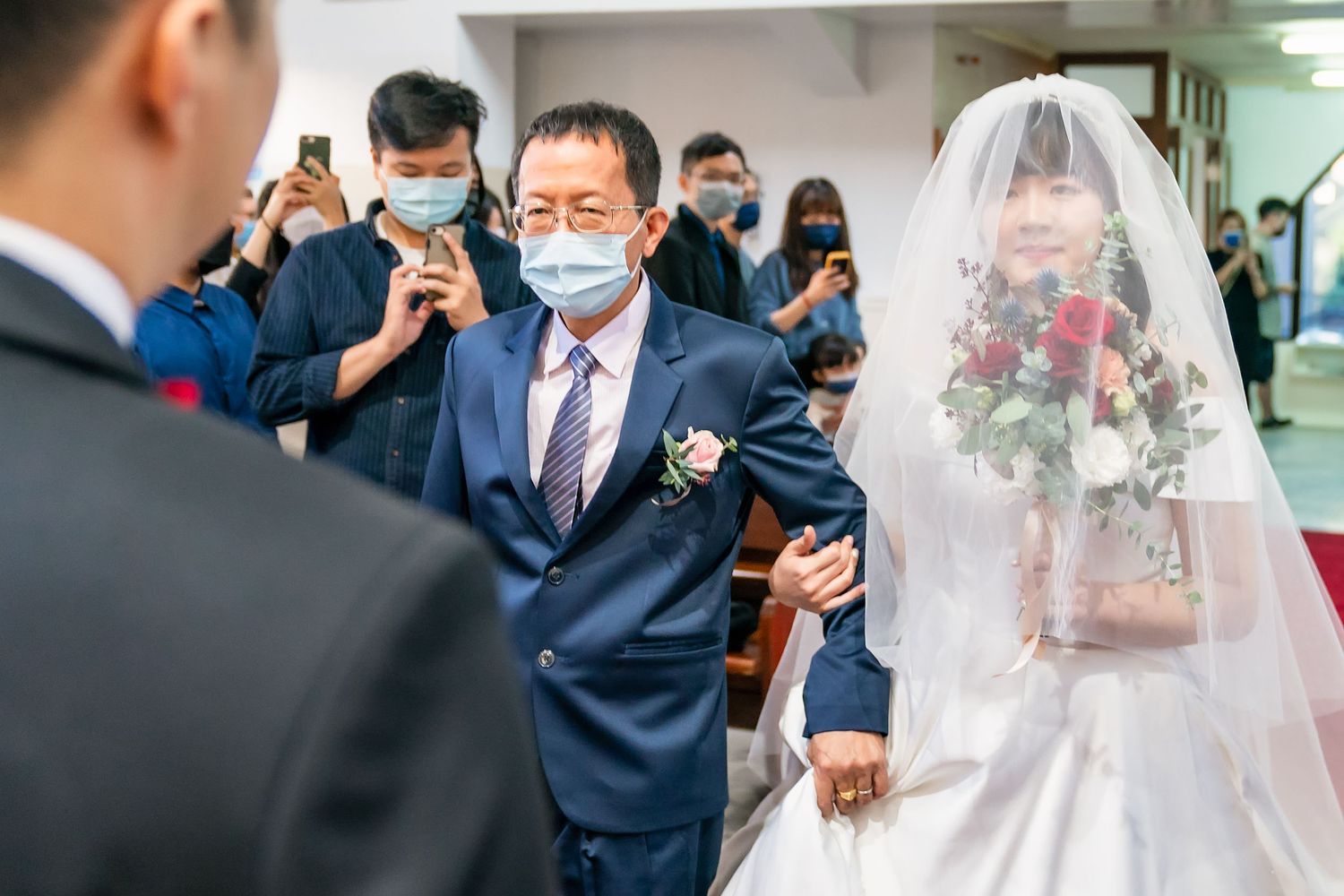 Wedding processional down church aisle with attendees wearing protective face masks.