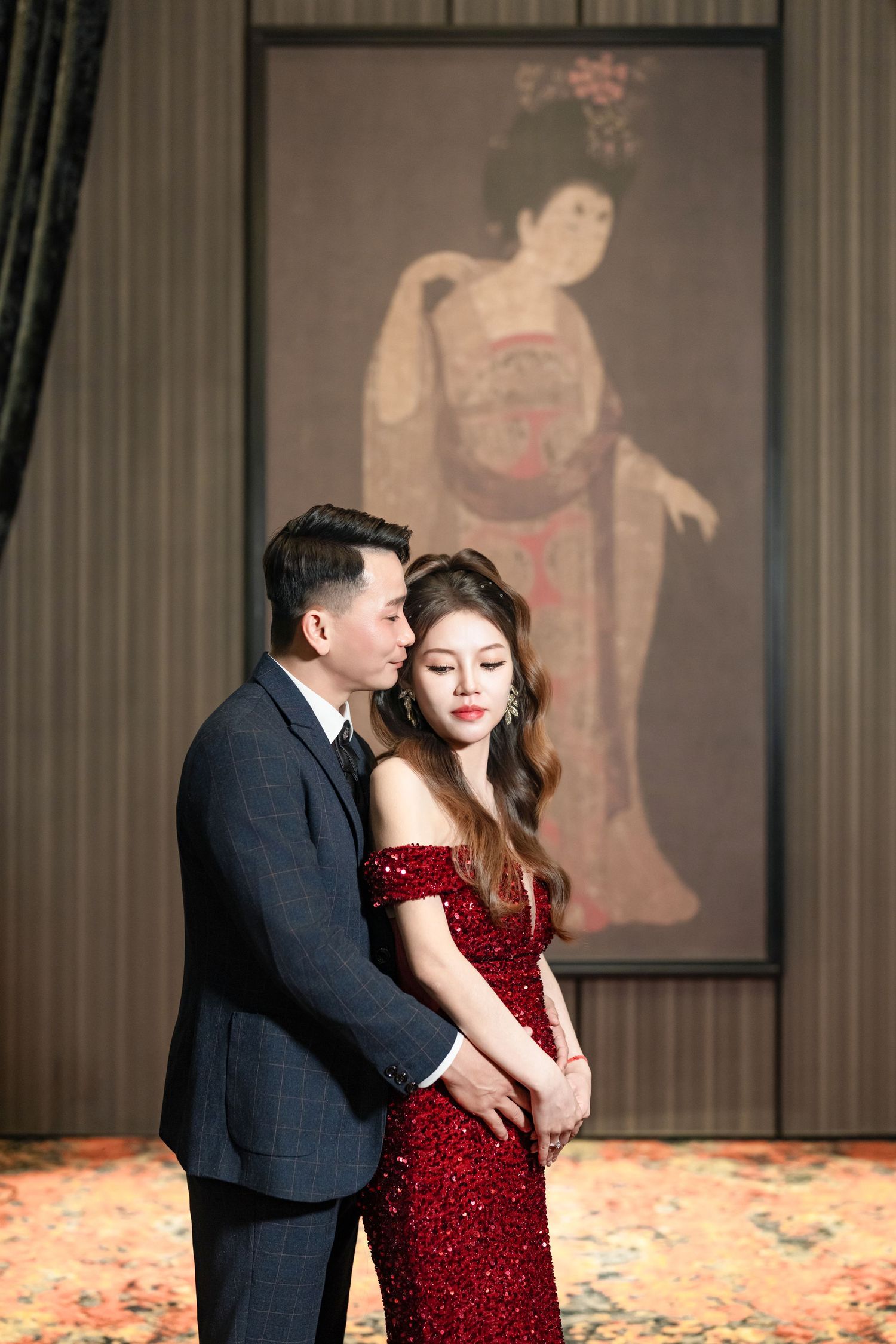 A couple in formal attire share an intimate dance moment on a stage with scattered rose petals.
