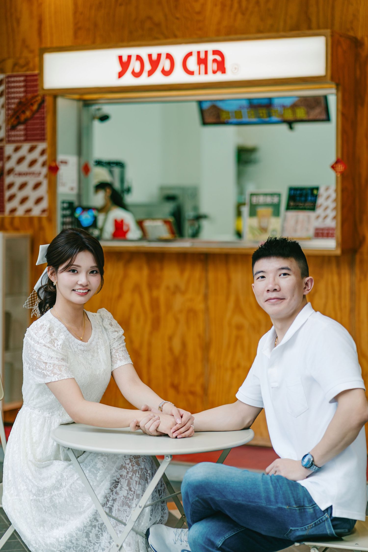 Young couple in white tops sit together at a casual restaurant table having a conversation.