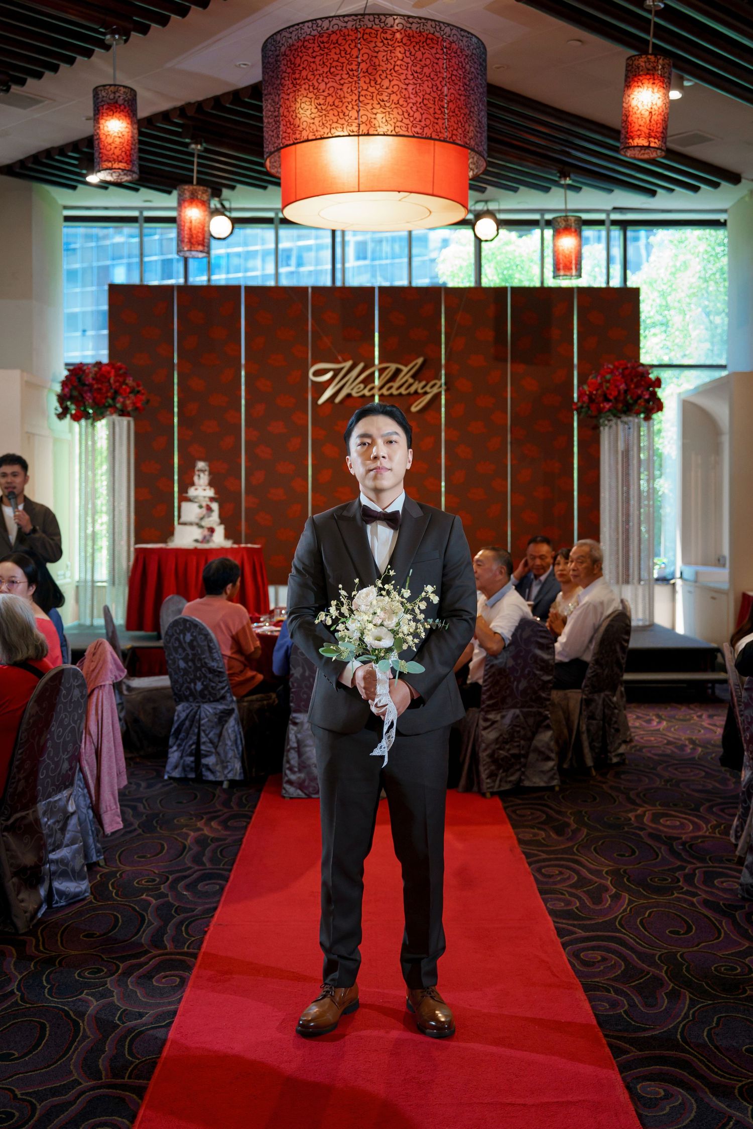 Wedding ceremony setup in a modern venue with red carpet aisle, pendant lighting, and brick accent walls.