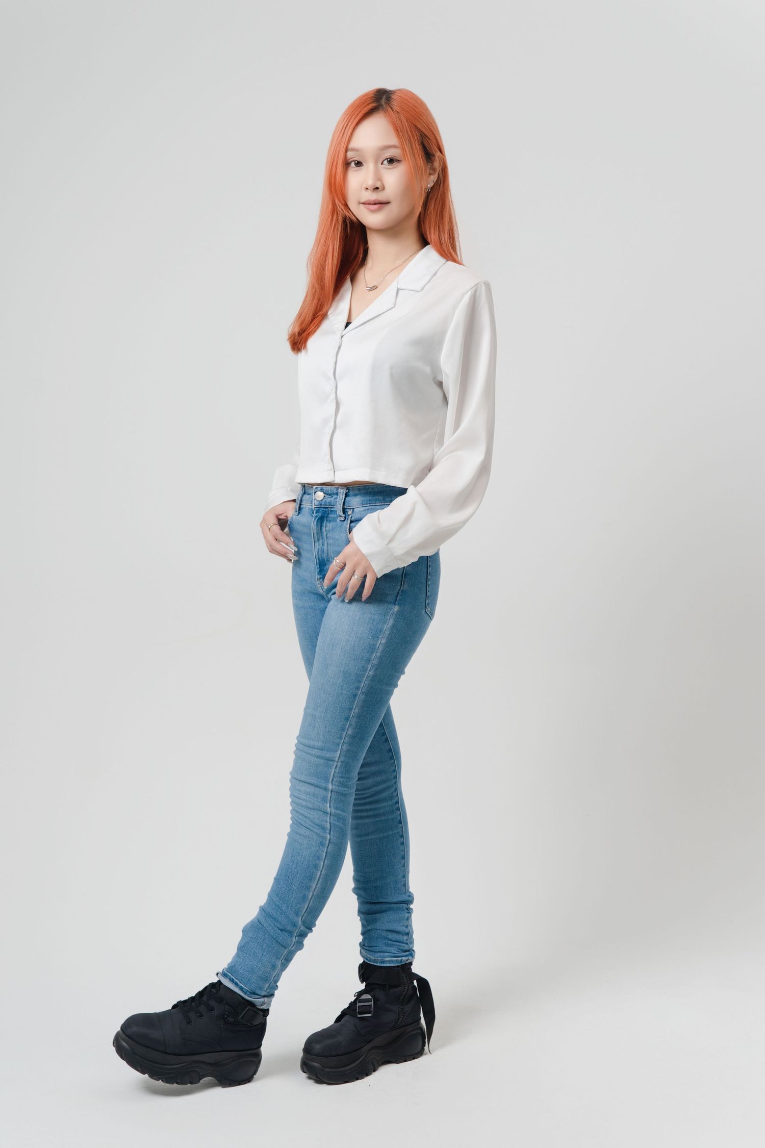 A figure in a white button-down shirt and blue jeans strikes different poses against a light gray studio backdrop.