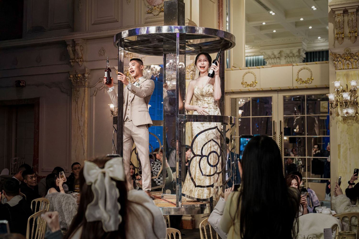 A group of people browse clothing and accessories in an elegant retail boutique with ornate decor and lighting.