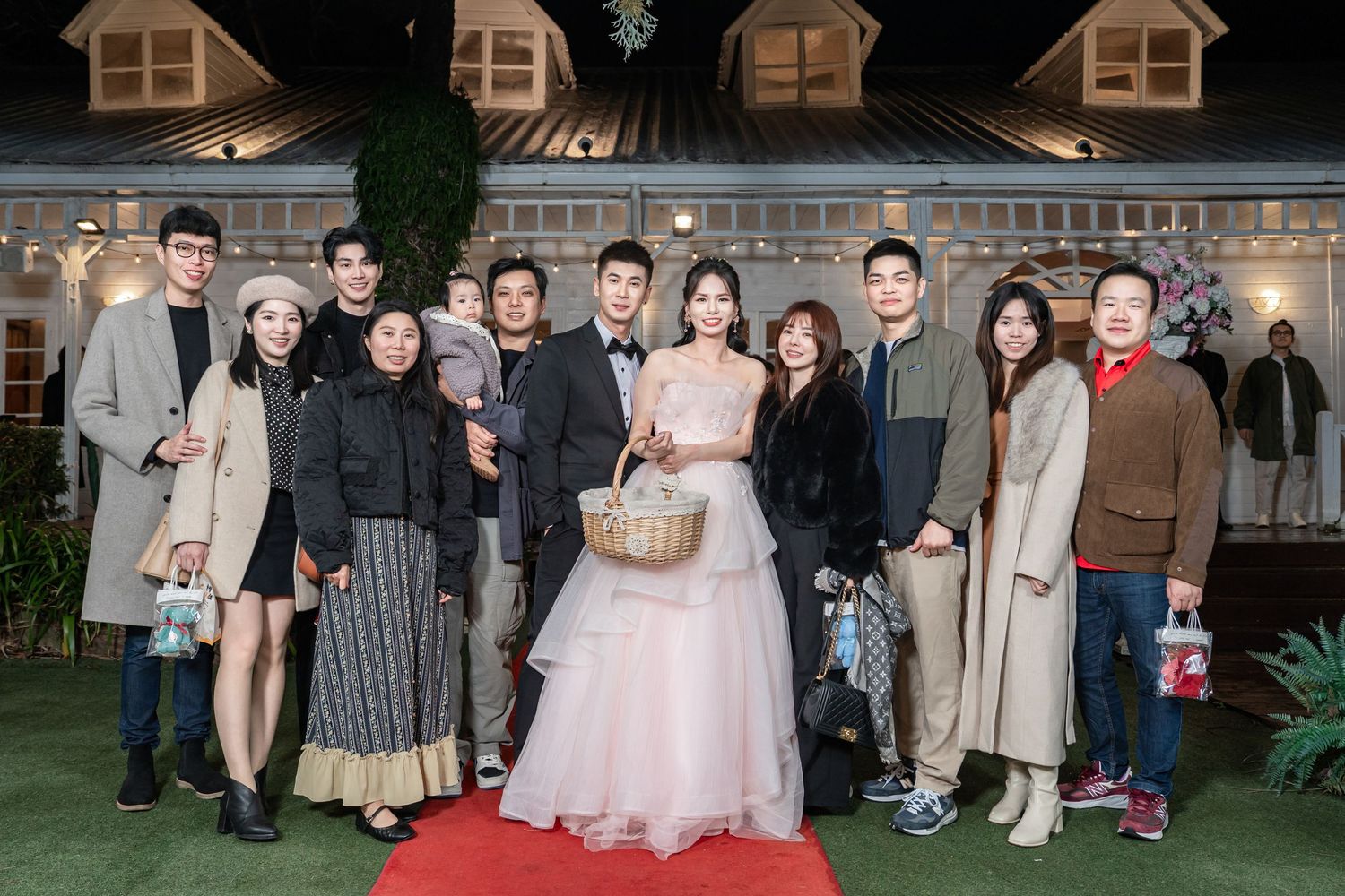 Multiple groups of wedding guests pose for photos outside a venue with rustic architectural details.