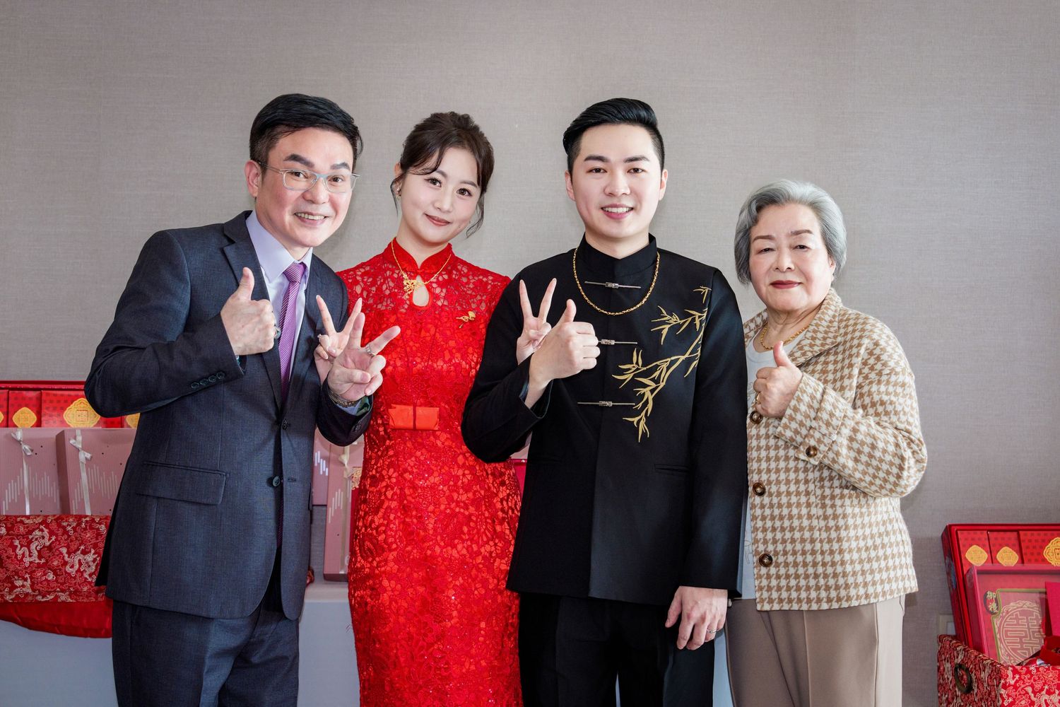 A group of people celebrating Chinese New Year wearing traditional red and formal attire pose together.