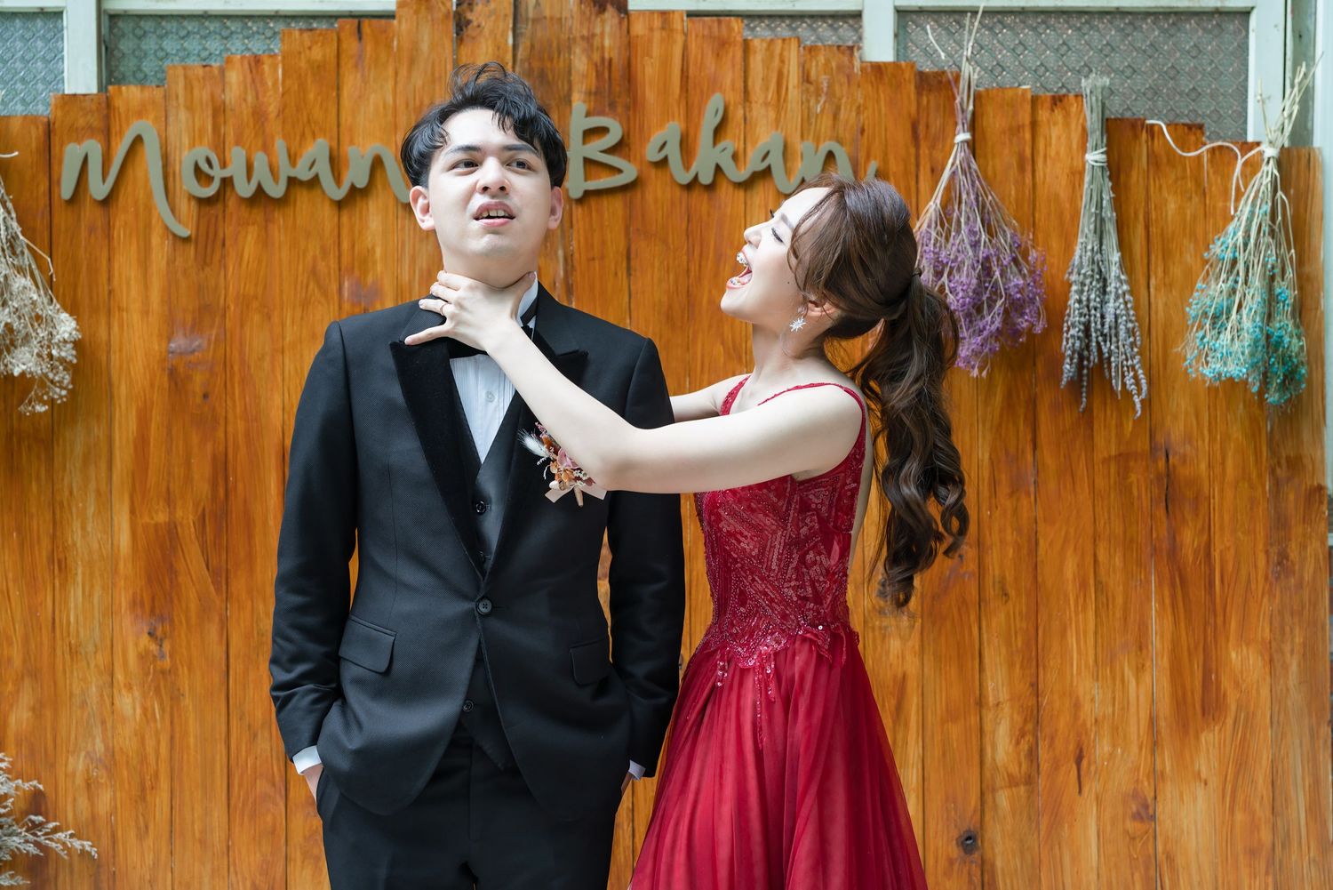 Candid formal portrait against rustic wooden wall with text signage.