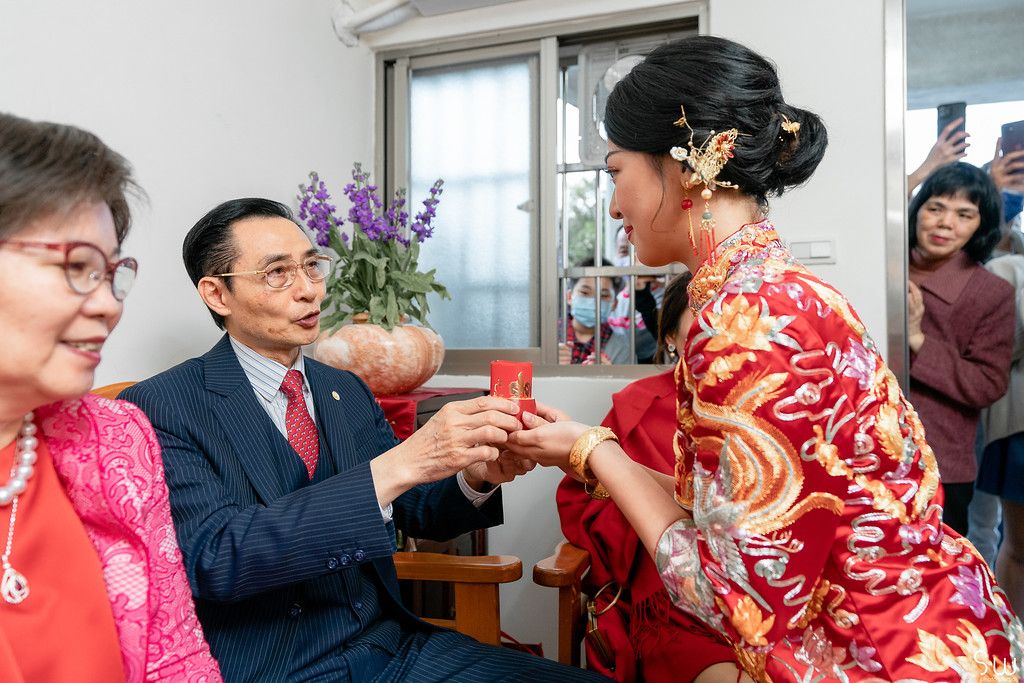 Tea serving ceremony with family members exchanging cups during Chinese wedding celebration.
