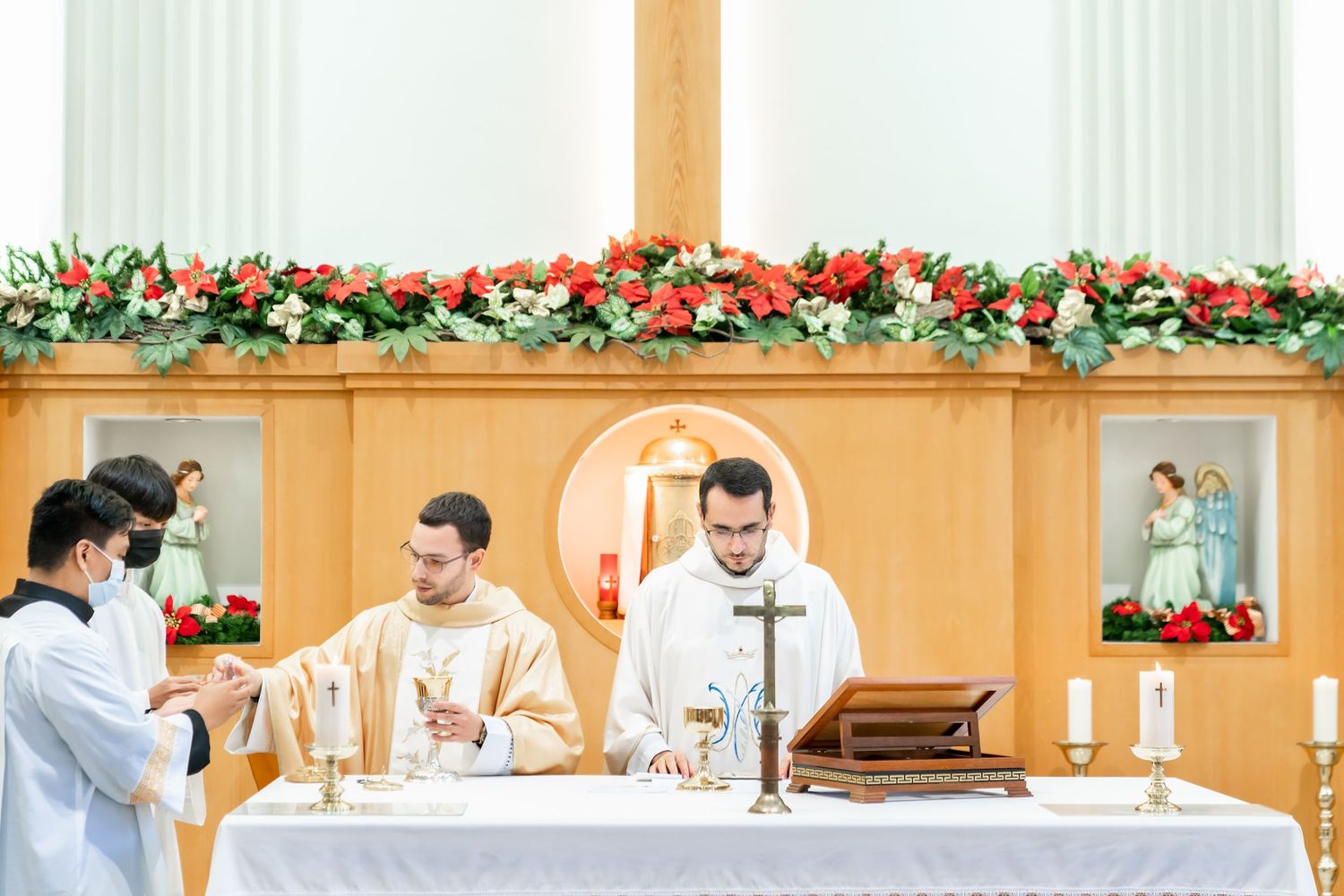 Catholic priests performing religious rituals at a decorated altar during a ceremony.