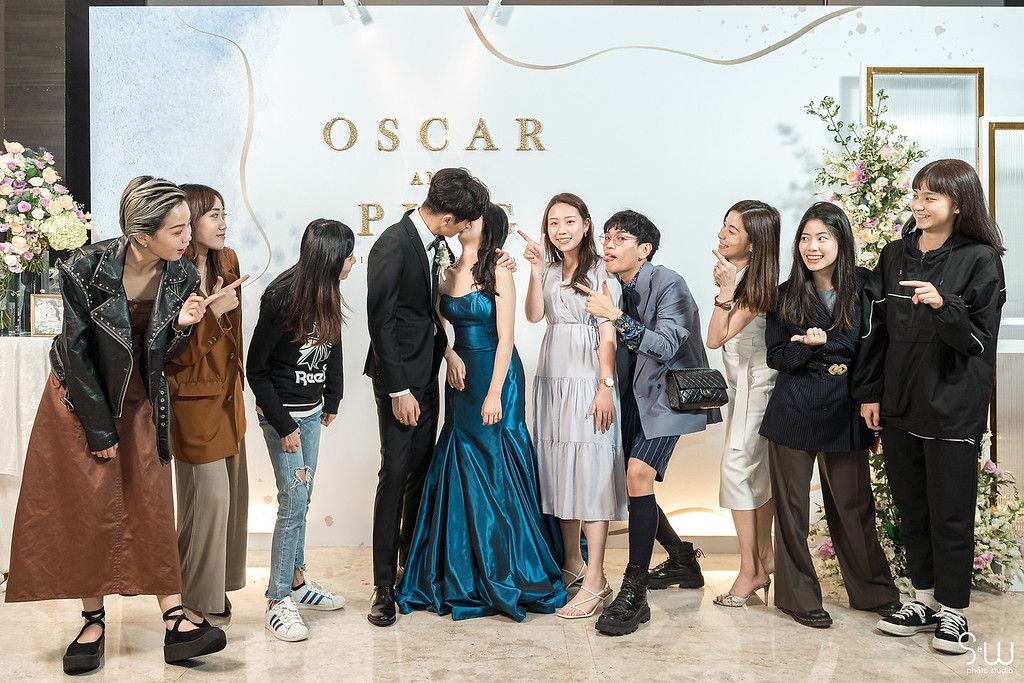 Friends gather for a casual group photo at a wedding celebration with an elegant backdrop.
