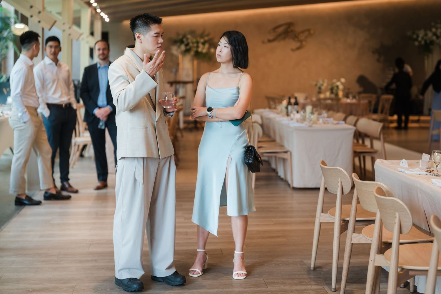 Two people in light blue attire stand and talk together in an elegant restaurant dining space.