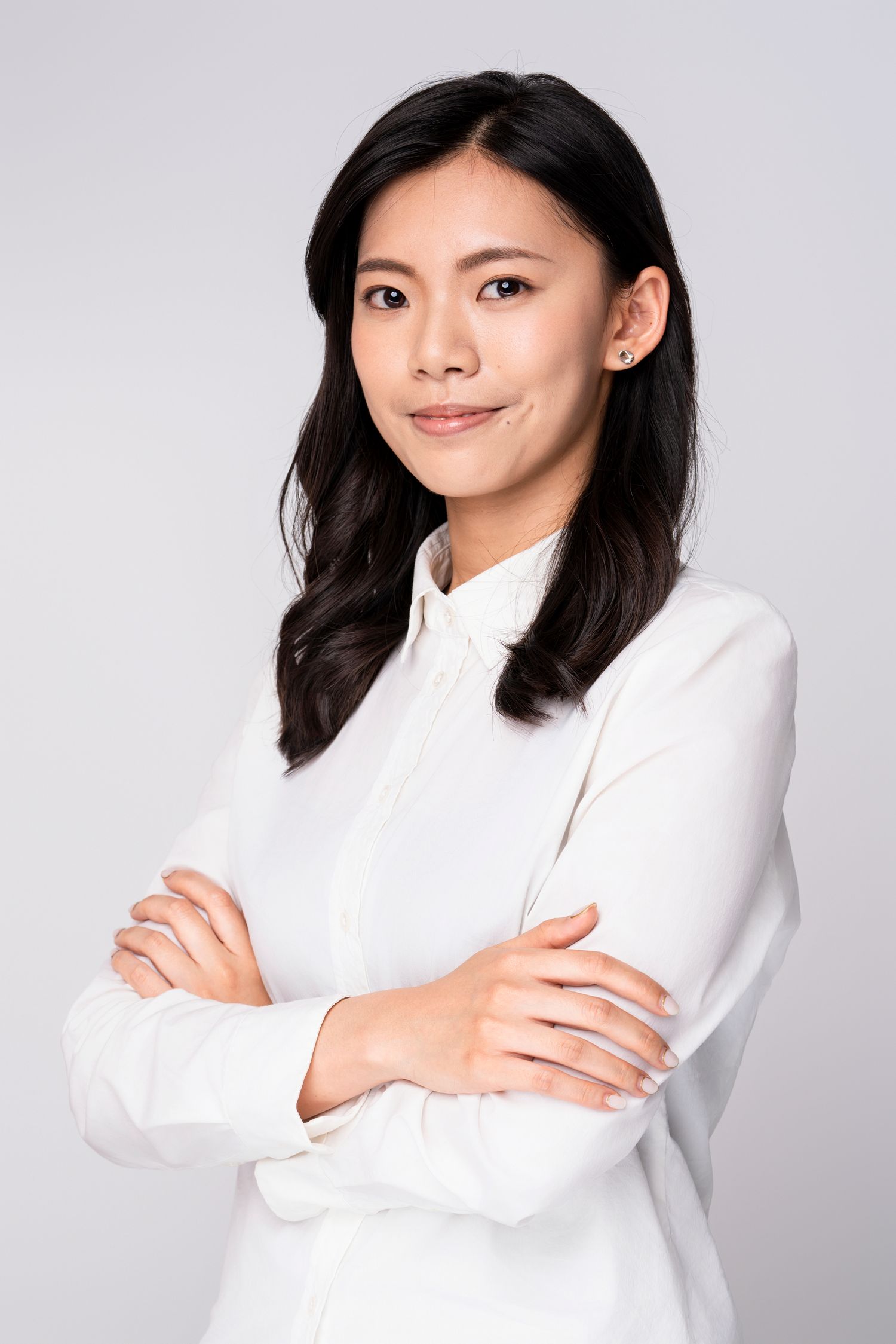 A person in a white long-sleeved top poses confidently against a light gray background in a photo series.