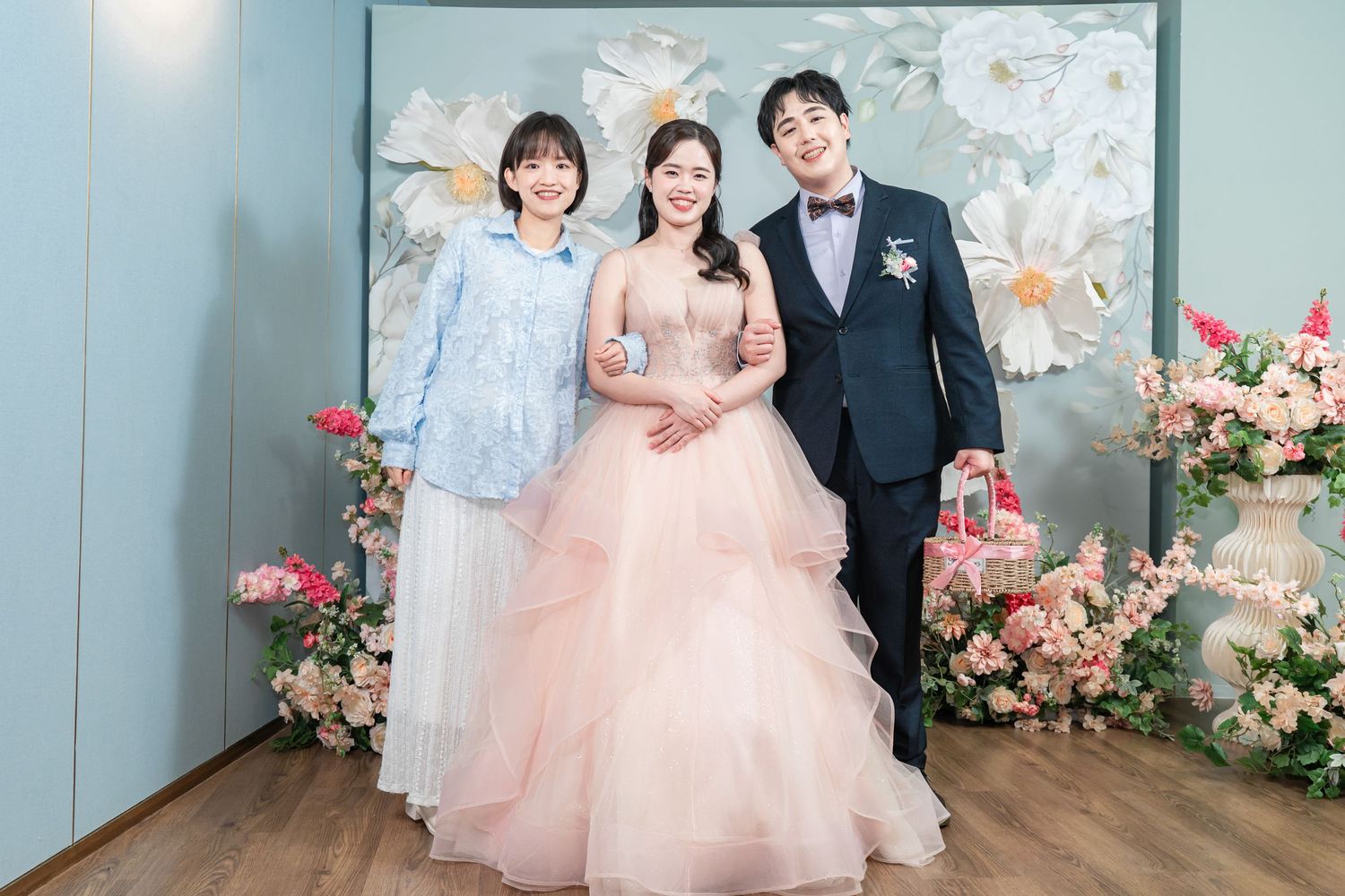 Wedding party poses in front of a floral backdrop wearing formal attire in pink and black.