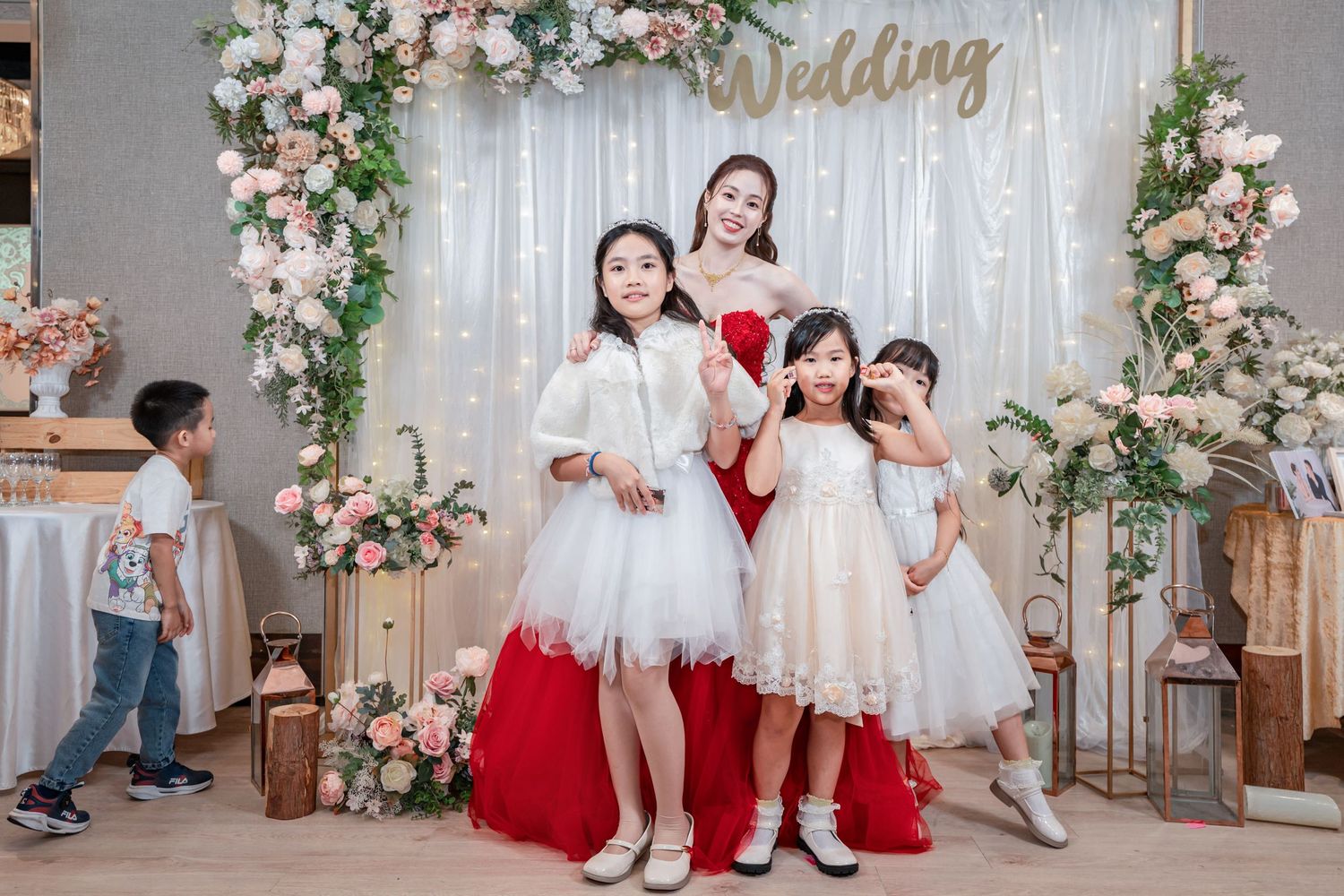 Wedding photo backdrop with pink and white floral arrangements and elegant gold lettering decoration.