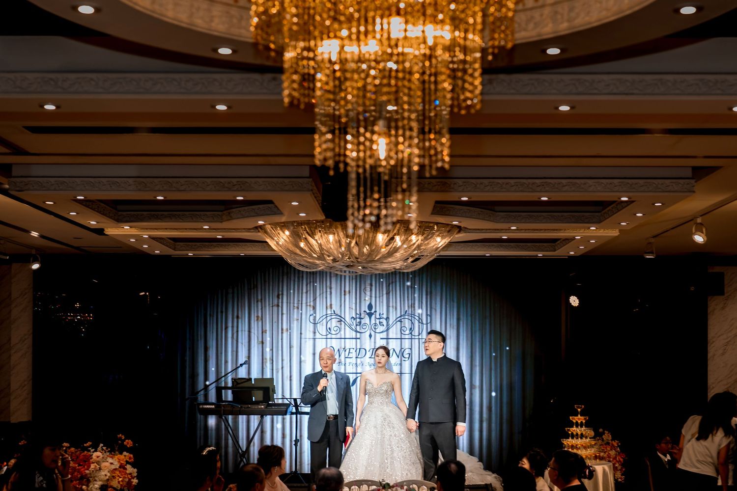 Elegant wedding reception venue with crystal chandeliers and dramatic blue lighting.