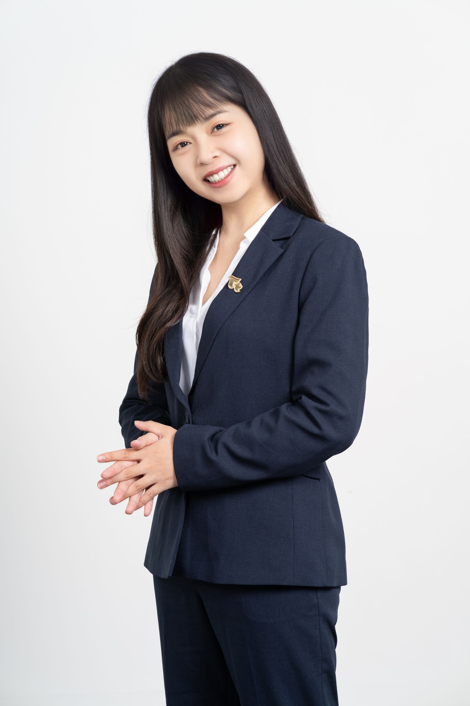 Professional portrait of someone in a navy business suit and white blouse standing against a white background.
