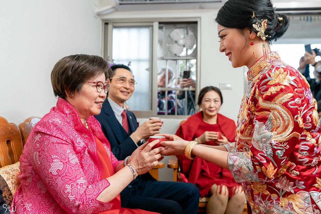 Traditional tea ceremony with family members dressed in red and formal attire.