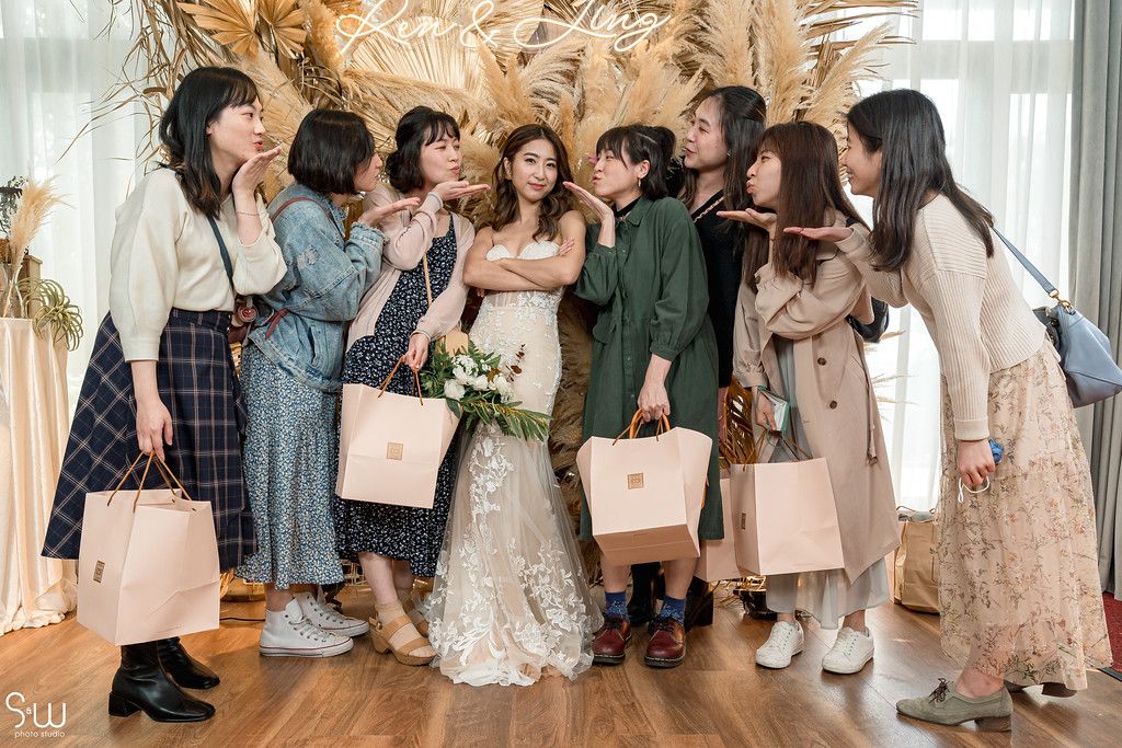Candid wedding party moment with guests in casual chic attire against dried grass backdrop.