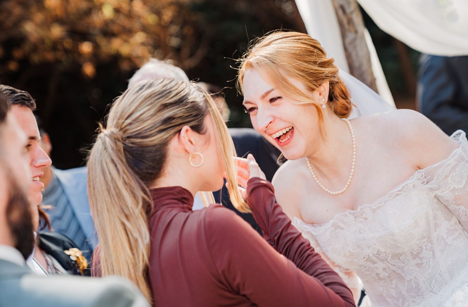 Candid moment of joyful interaction during outdoor wedding reception.