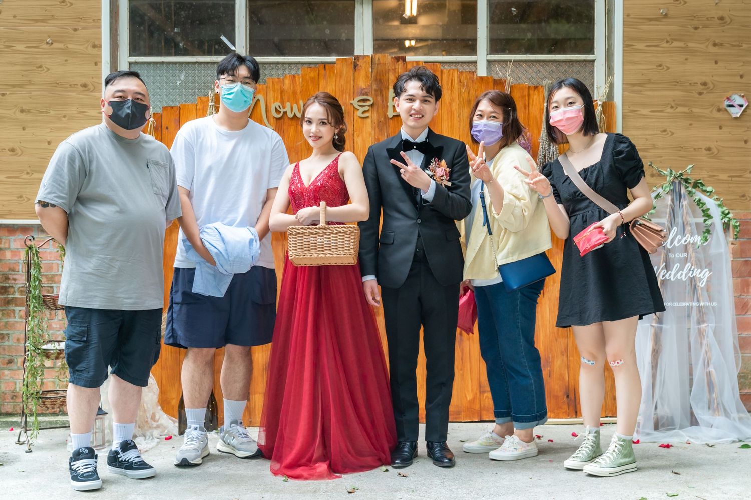 A group poses in mixed casual and formal wear against an orange backdrop with decorative elements.