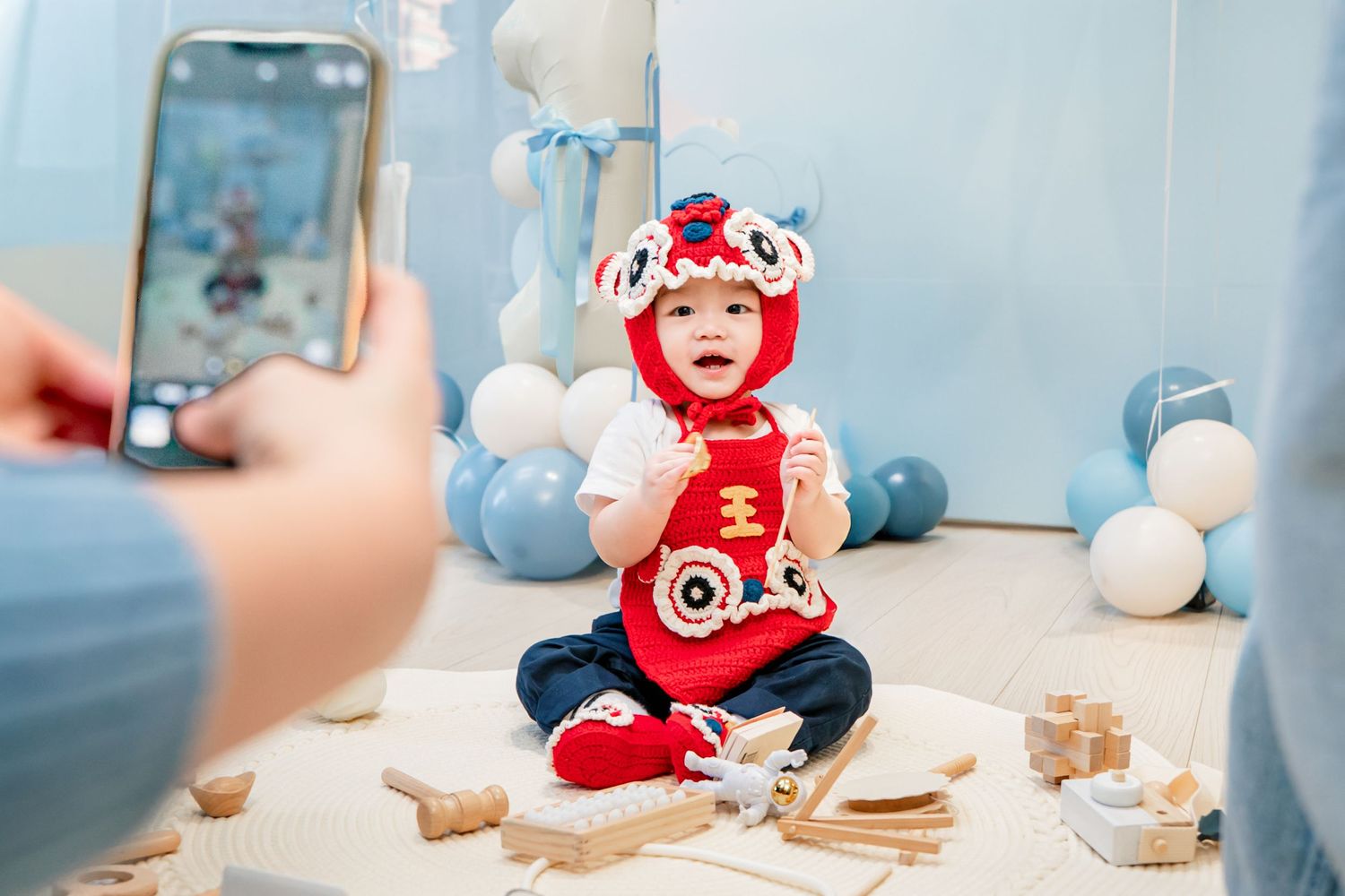 A red and white holiday-themed baby photoshoot setup with milk and cookies against a light blue background.