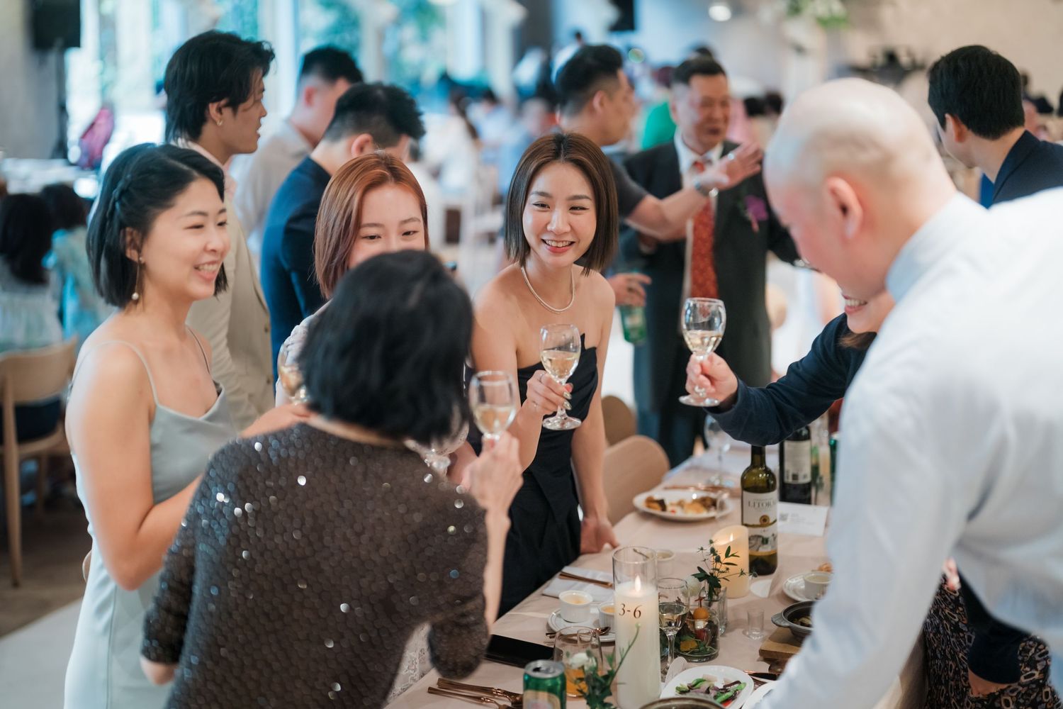 Wedding guests enjoy drinks and conversation at an elegant reception dinner table with festive atmosphere.