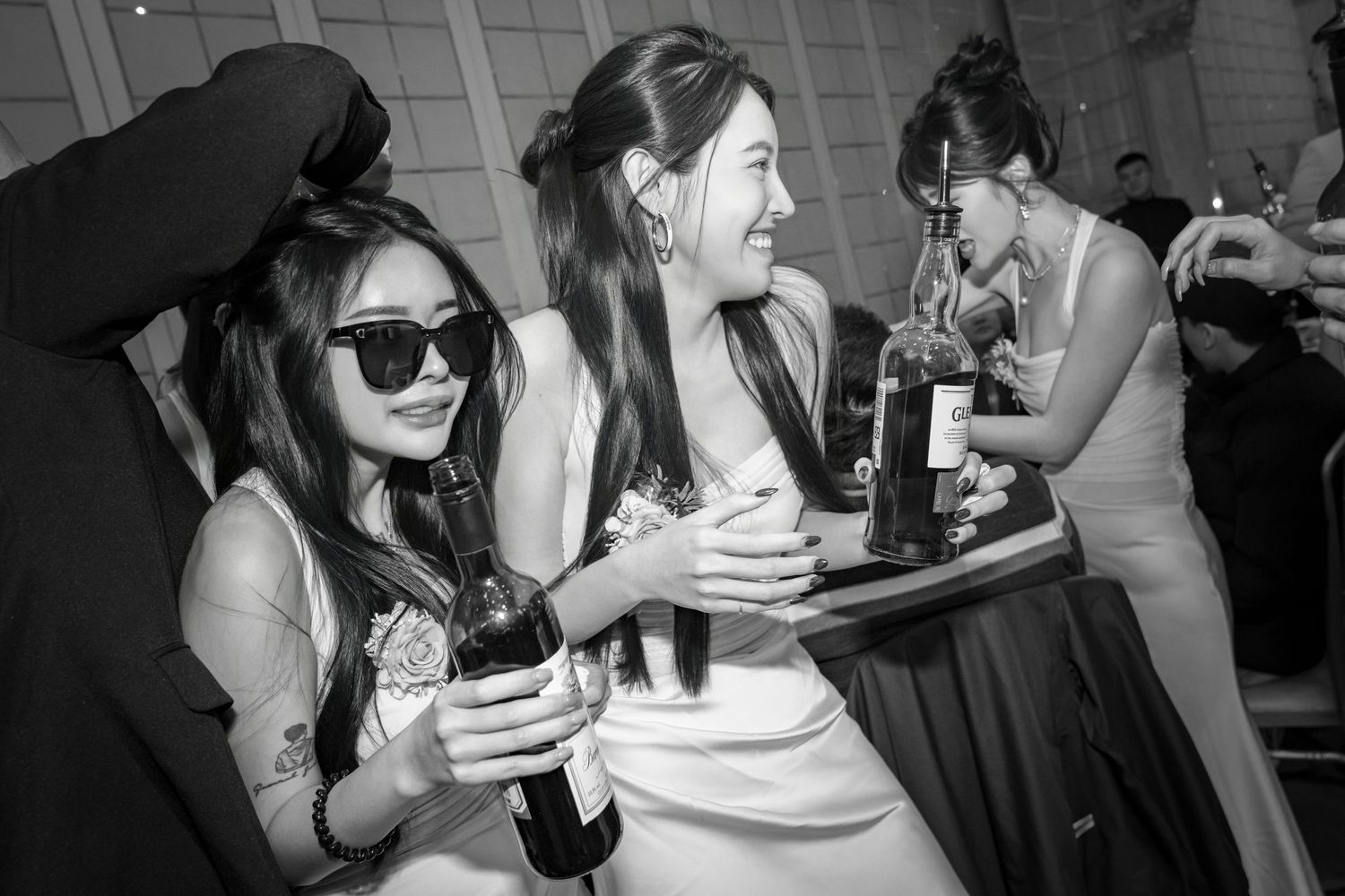 A group of friends laughing and enjoying drinks together at a social gathering in black and white photography.