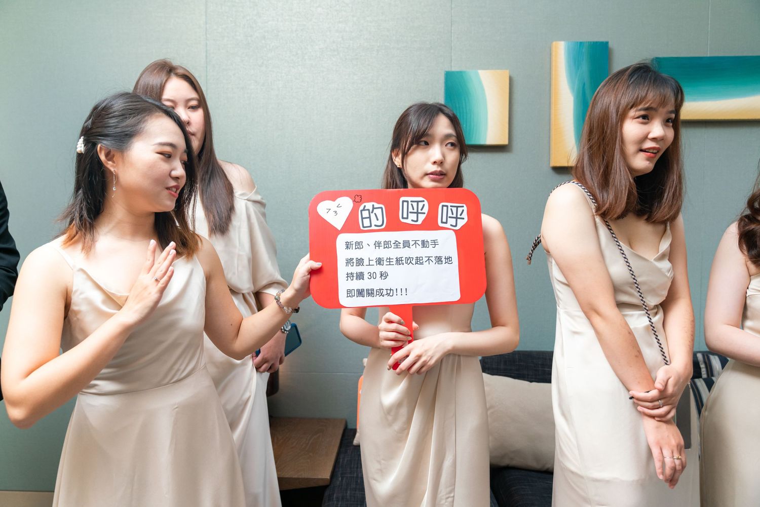 A group in beige dresses poses together while one person holds a red clapperboard during a production.