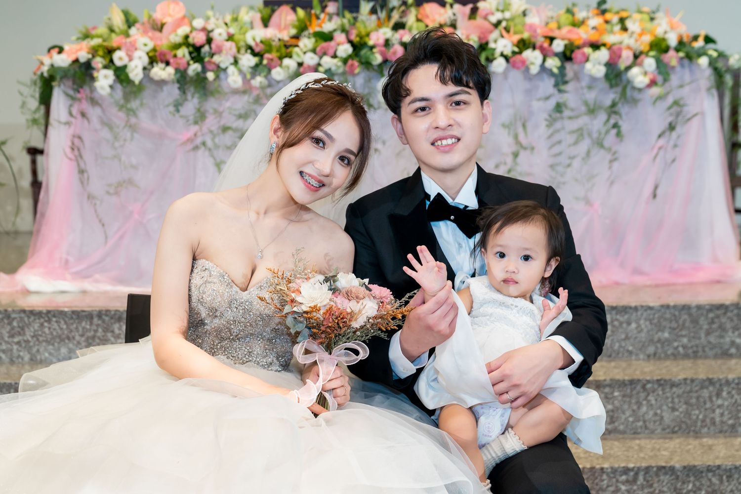 Wedding portrait in front of floral arch backdrop with beautiful pink and white blooms.