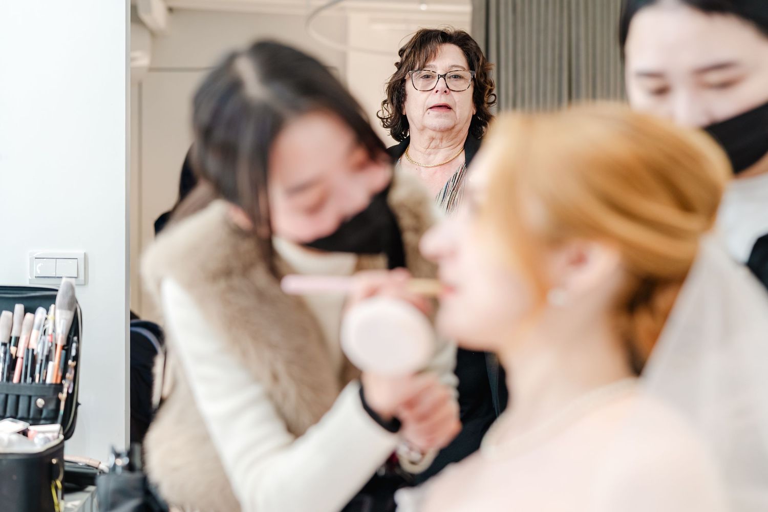 Professional makeup artists working together during bridal preparation.