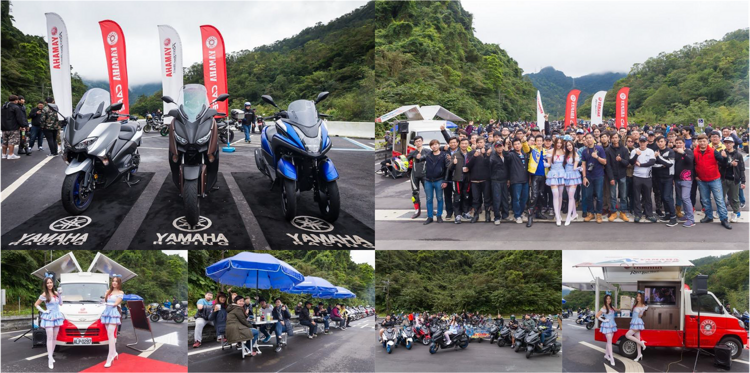 Motorcycle gathering with display vehicles and attendees under flags and banners outdoors.