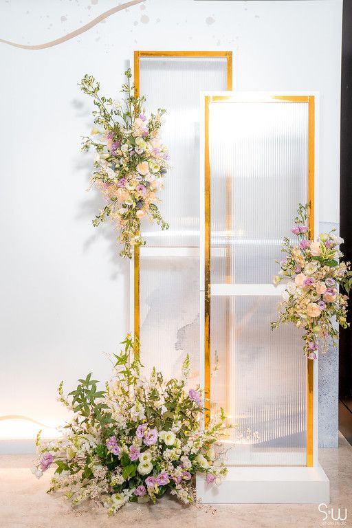 Elegant wedding backdrop display with gold geometric frames and delicate floral arrangements in pink and white.