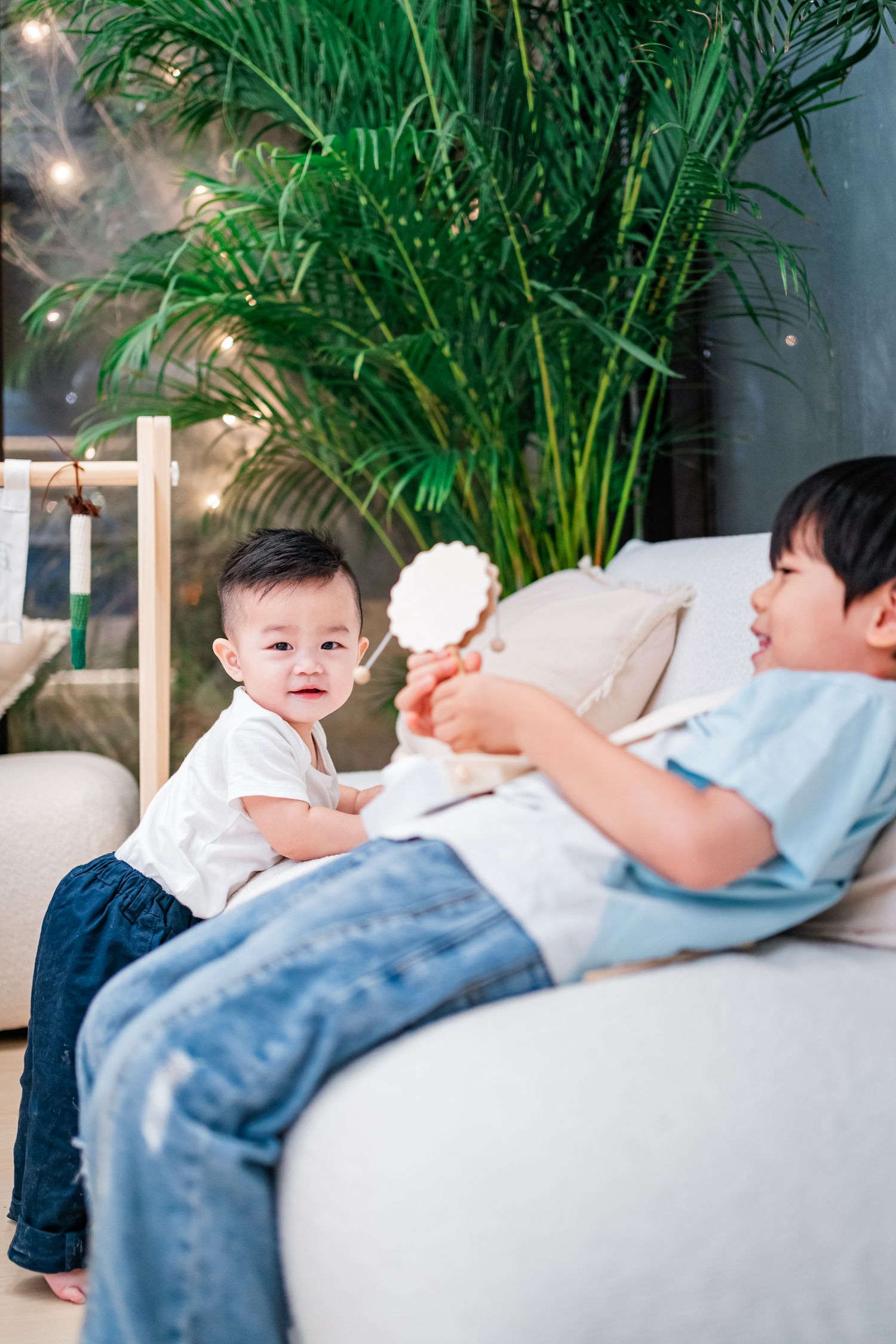 A series of five connected images showing a tender moment between a parent and baby relaxing on a couch with plants nearby.