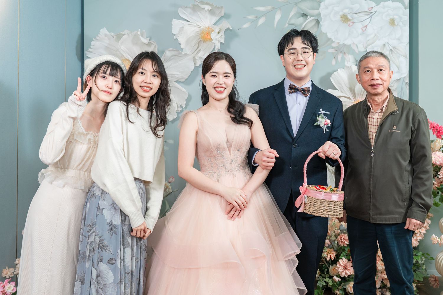 A group of people pose together at a wedding celebration in formal attire and traditional dress.