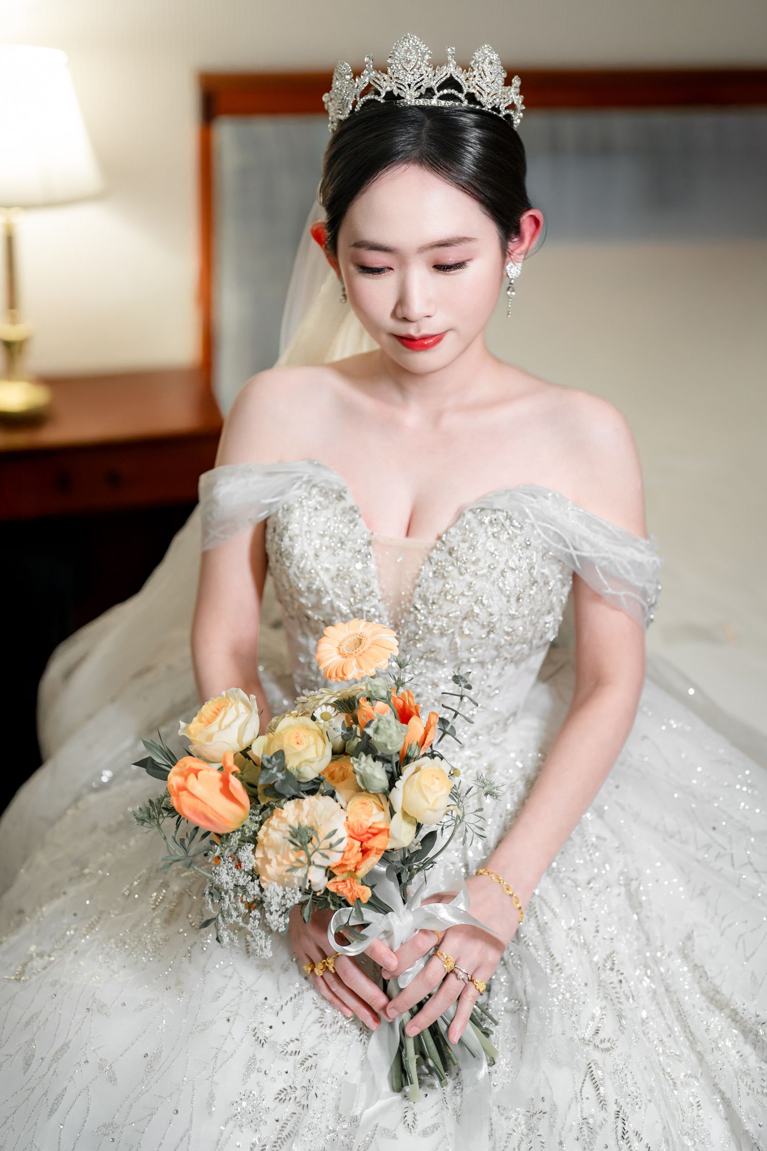 A stunning white wedding gown with intricate beading and embellishments paired with a delicate peach rose bouquet.