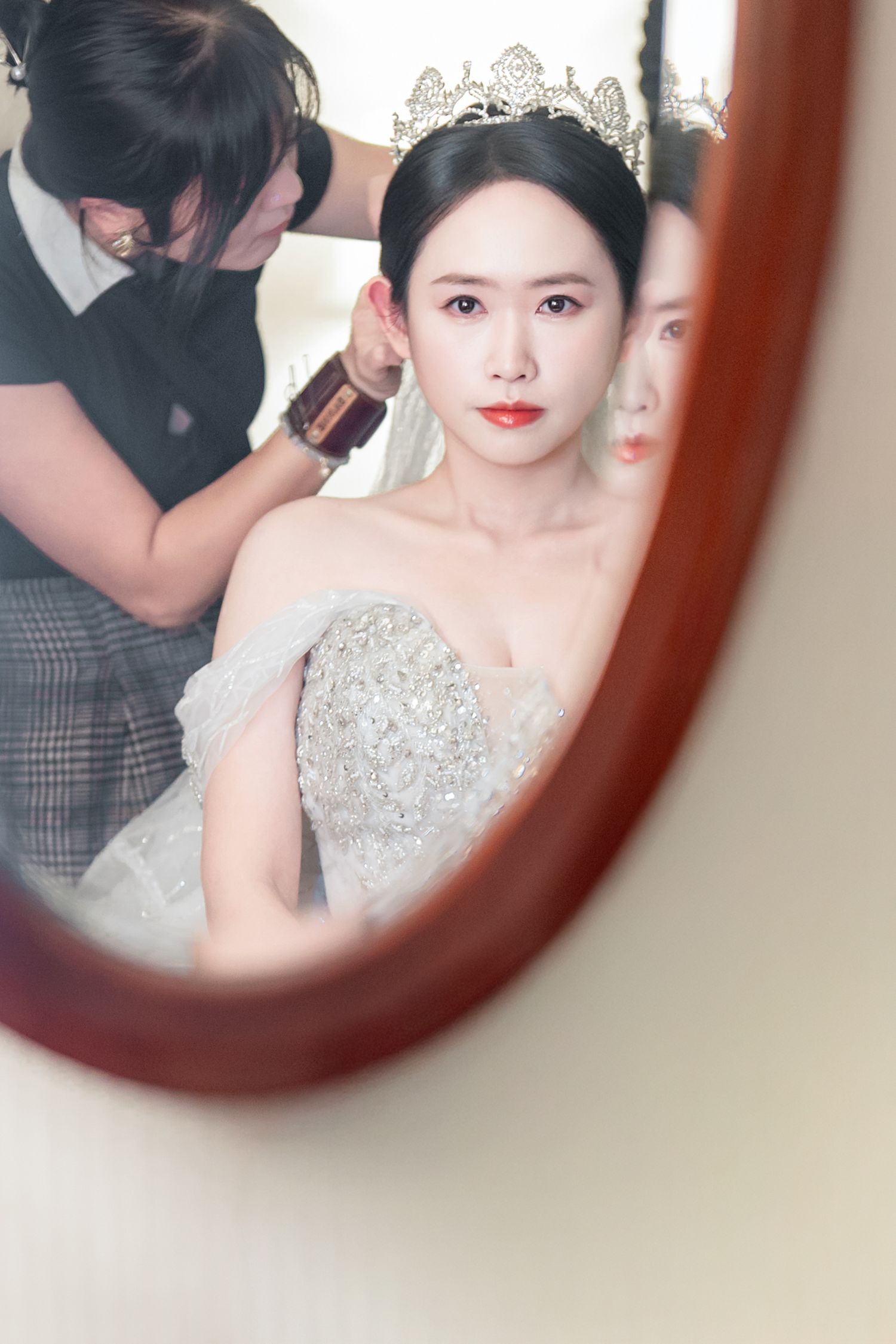 A series of mirror reflections show a person in an elegant white beaded dress with delicate makeup and styling.