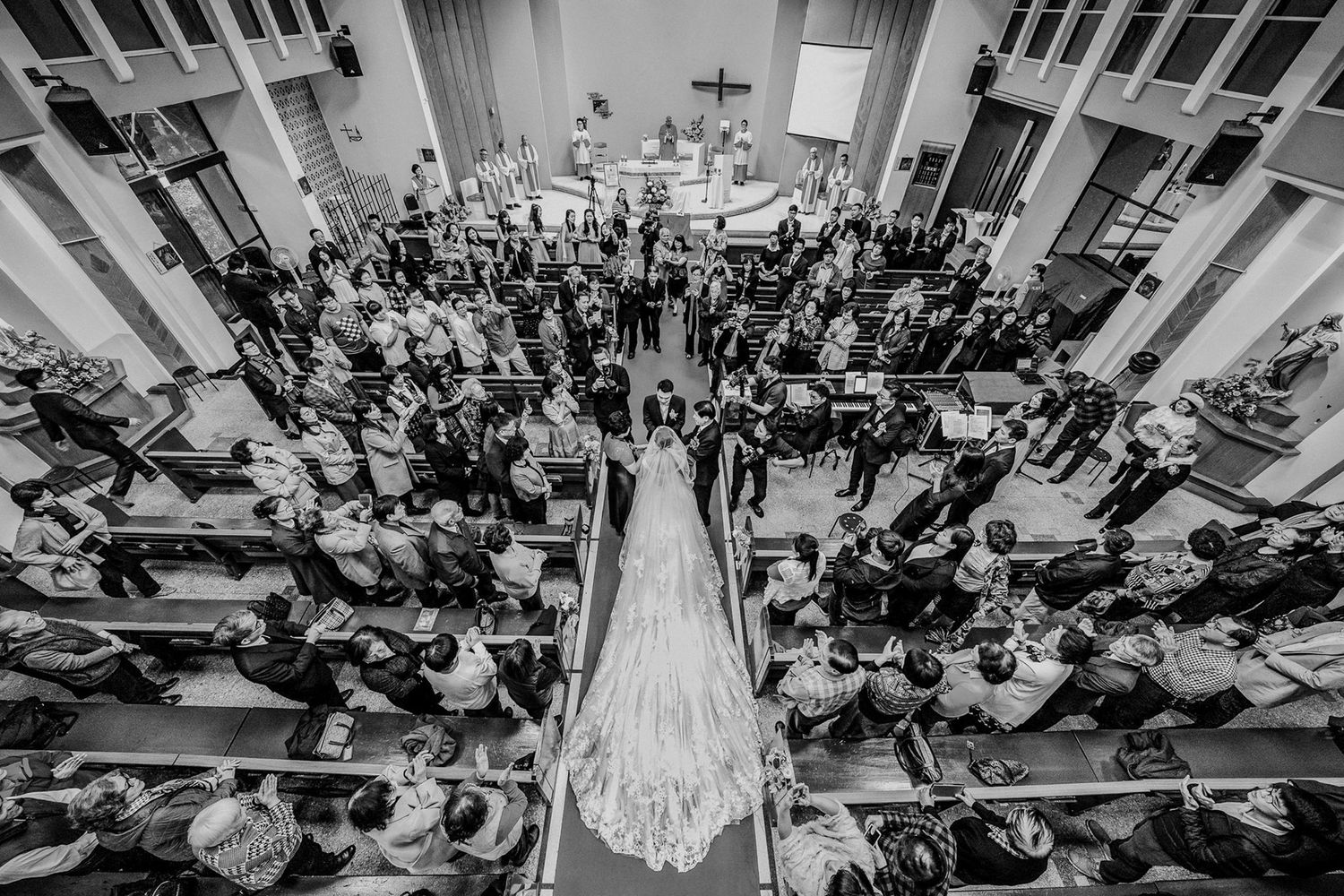 A black and white photo series showing different angles of a crowded church wedding ceremony with elegant decor.