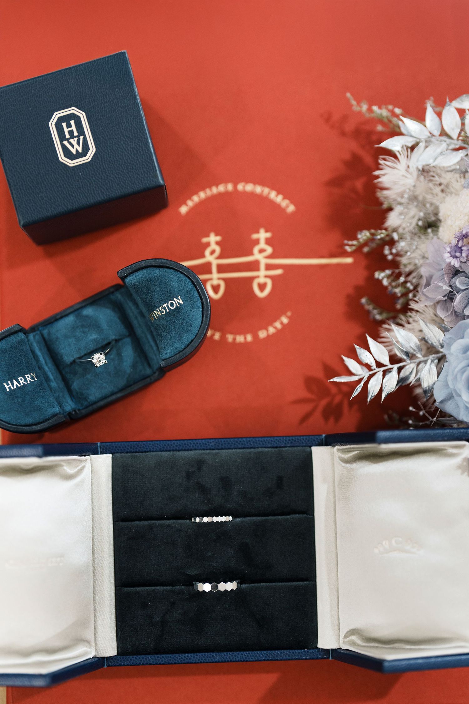 Navy blue jewelry boxes and gift packaging arranged on a red background with white decorative elements.