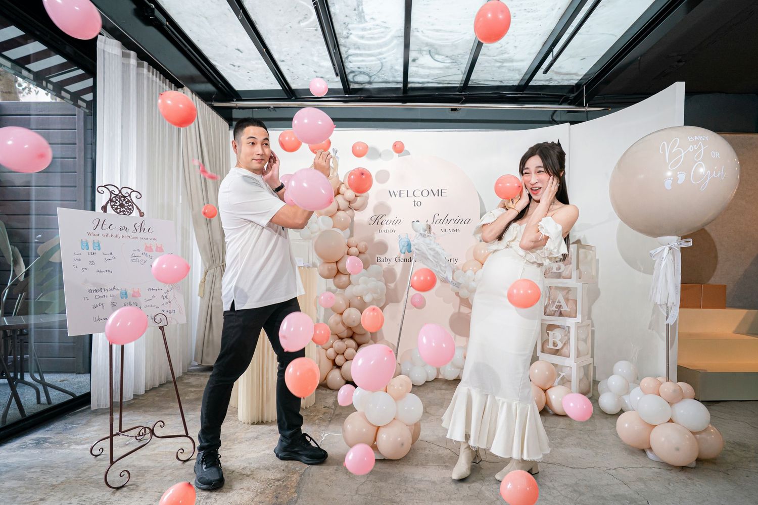 Panoramic view of a modern event space decorated with pink and peach balloons and white floral arrangements.