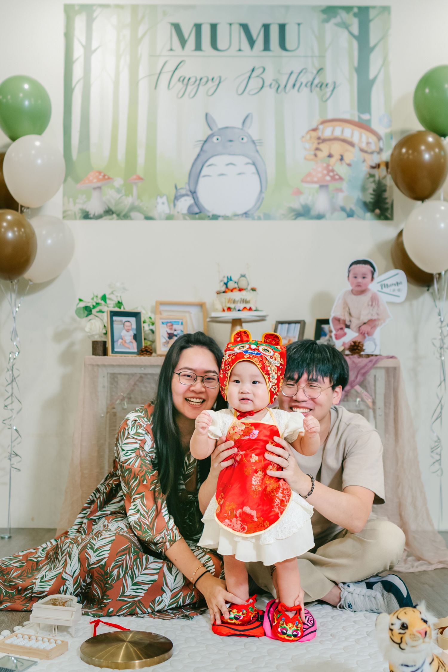 Birthday party scene with Totoro themed backdrop, white and brown balloons, and dessert table decorations.