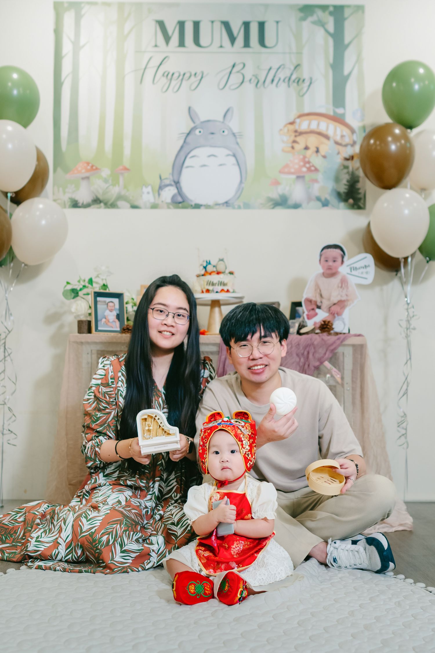 Birthday celebration scene with balloons, cushions and decorations in soft green and white tones.