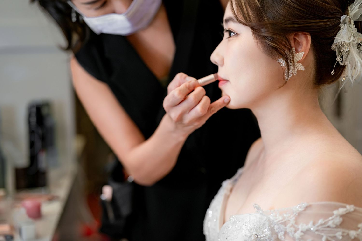 Professional makeup artist applying cosmetics to a bride during wedding preparation.
