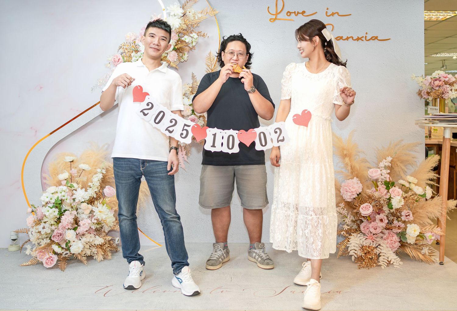 People stand together holding number signs while surrounded by floral decorations and party decorations.