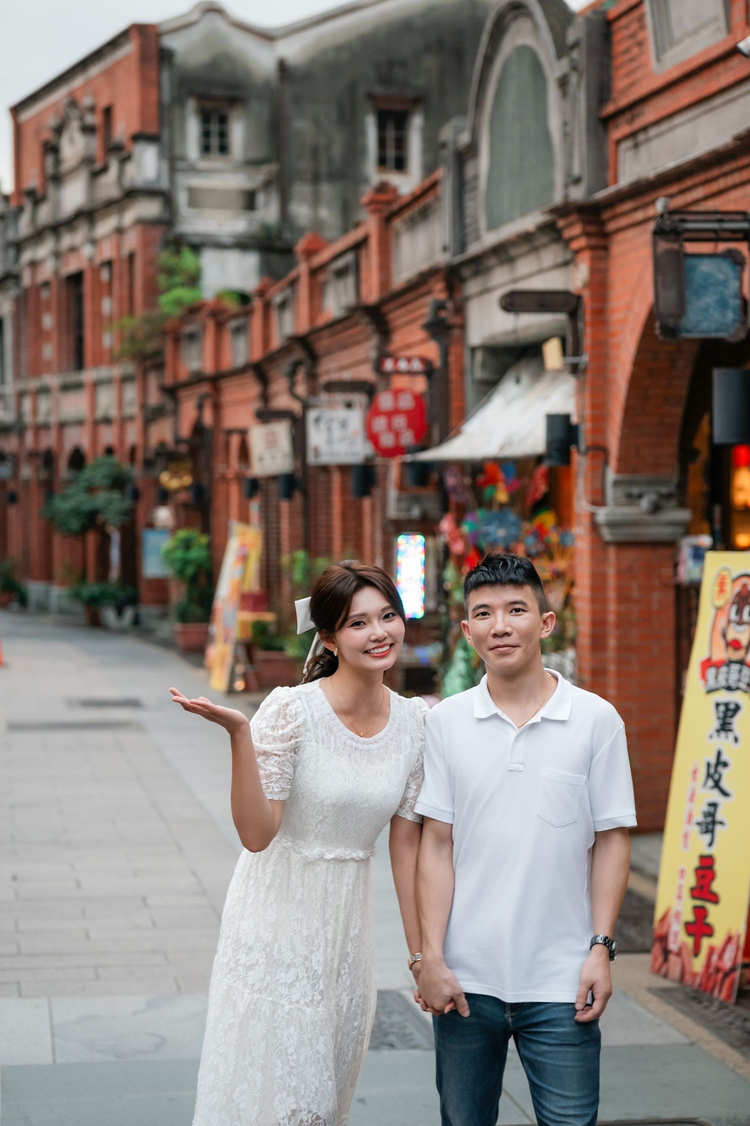 A couple walks and poses together along a historic red brick street with traditional Chinese architecture.