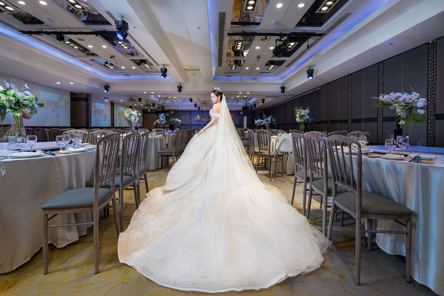 An elegant wedding reception venue with white decor and modern lighting in a spacious banquet hall.
