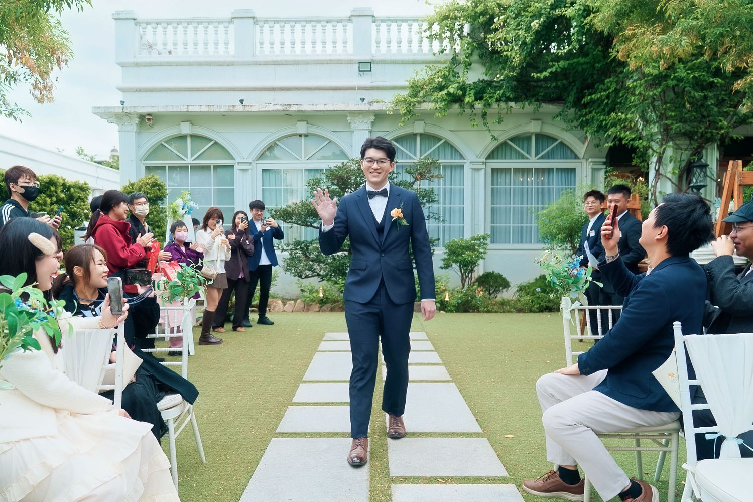 Wedding guests throw flower petals at a couple during a joyful outdoor ceremony exit.