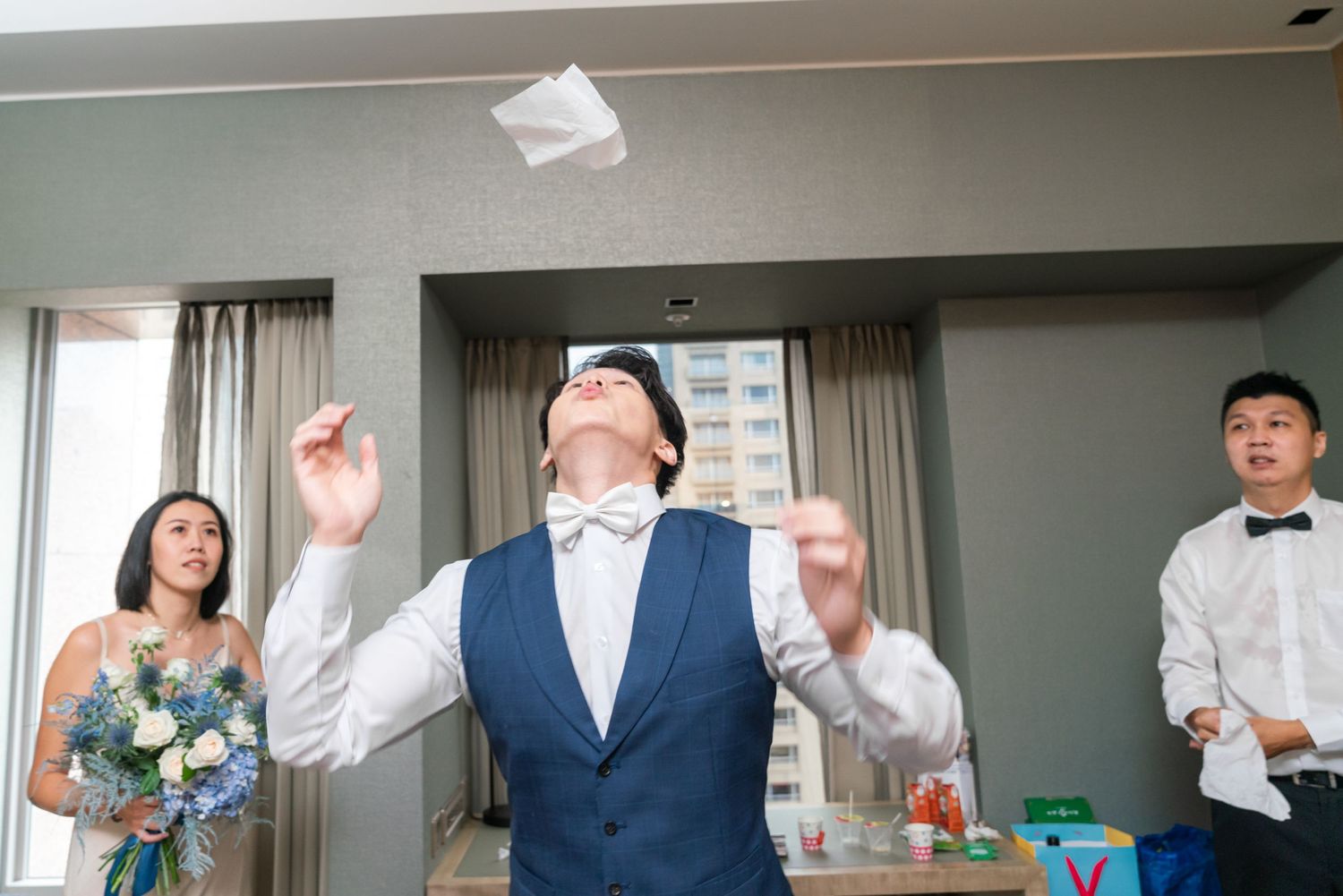 A person in a blue vest celebrates joyfully during a wedding celebration with others in attendance.